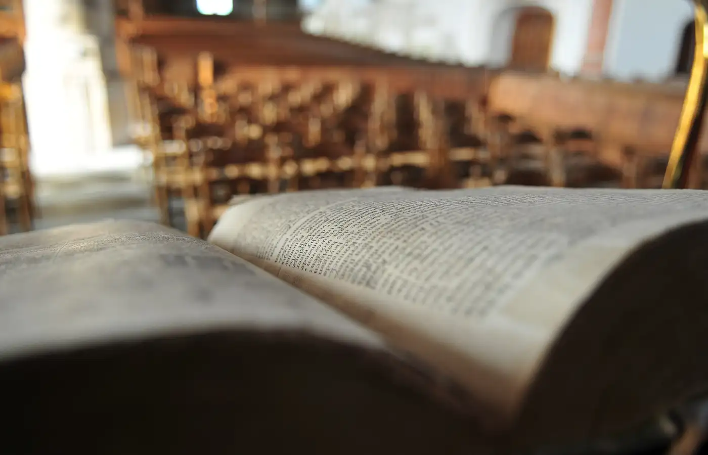 An open Statenbijbel on a lectern, with the pews of a Reformed church behind it.